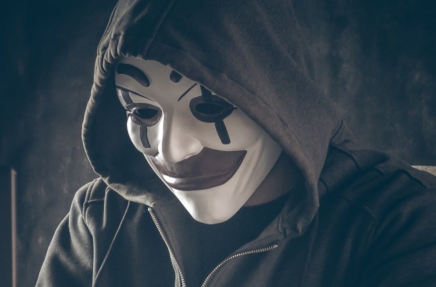 Computer hacker wearing clown mask