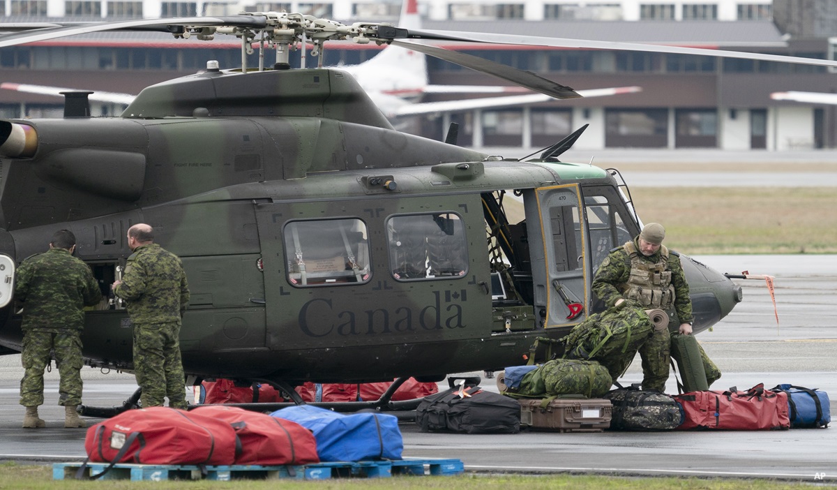 Canadian soldiers around a military helicopter