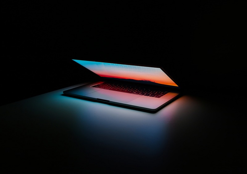Laptop with glowing screen in dark room