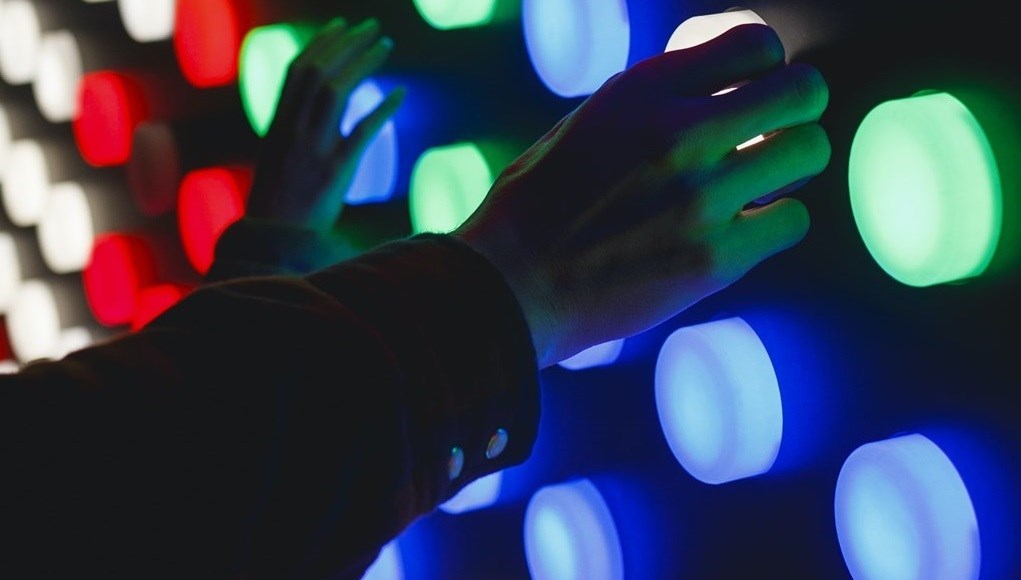 People touching multi-coloured lights