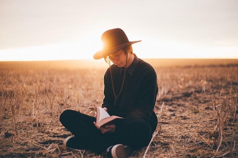 Person sitting in field reading a book