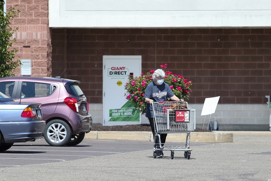 Femme avec un chariot devant un supermarché