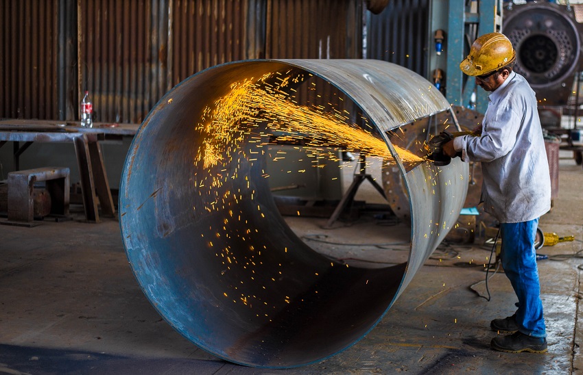 Construction worker cutting metal tube