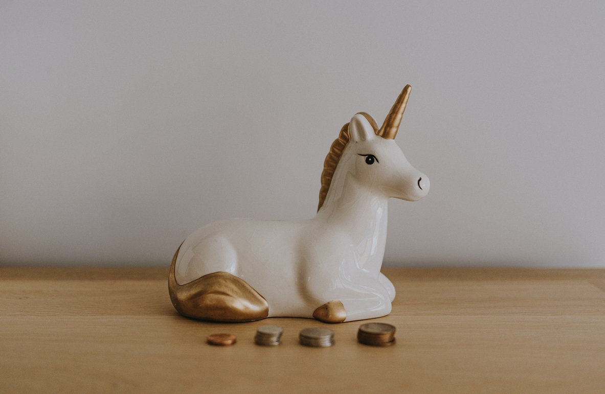 Unicorn in front of stacks of coins