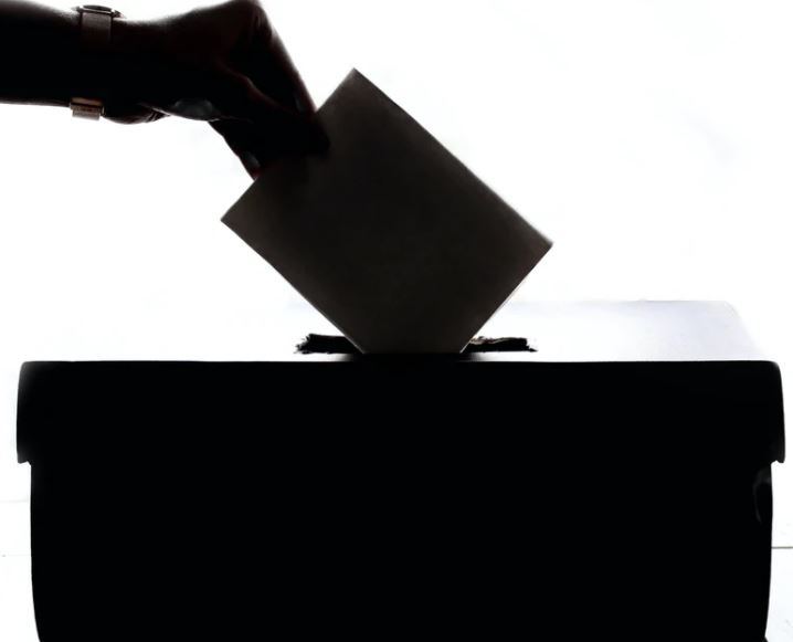 hand in shadow over a ballot box