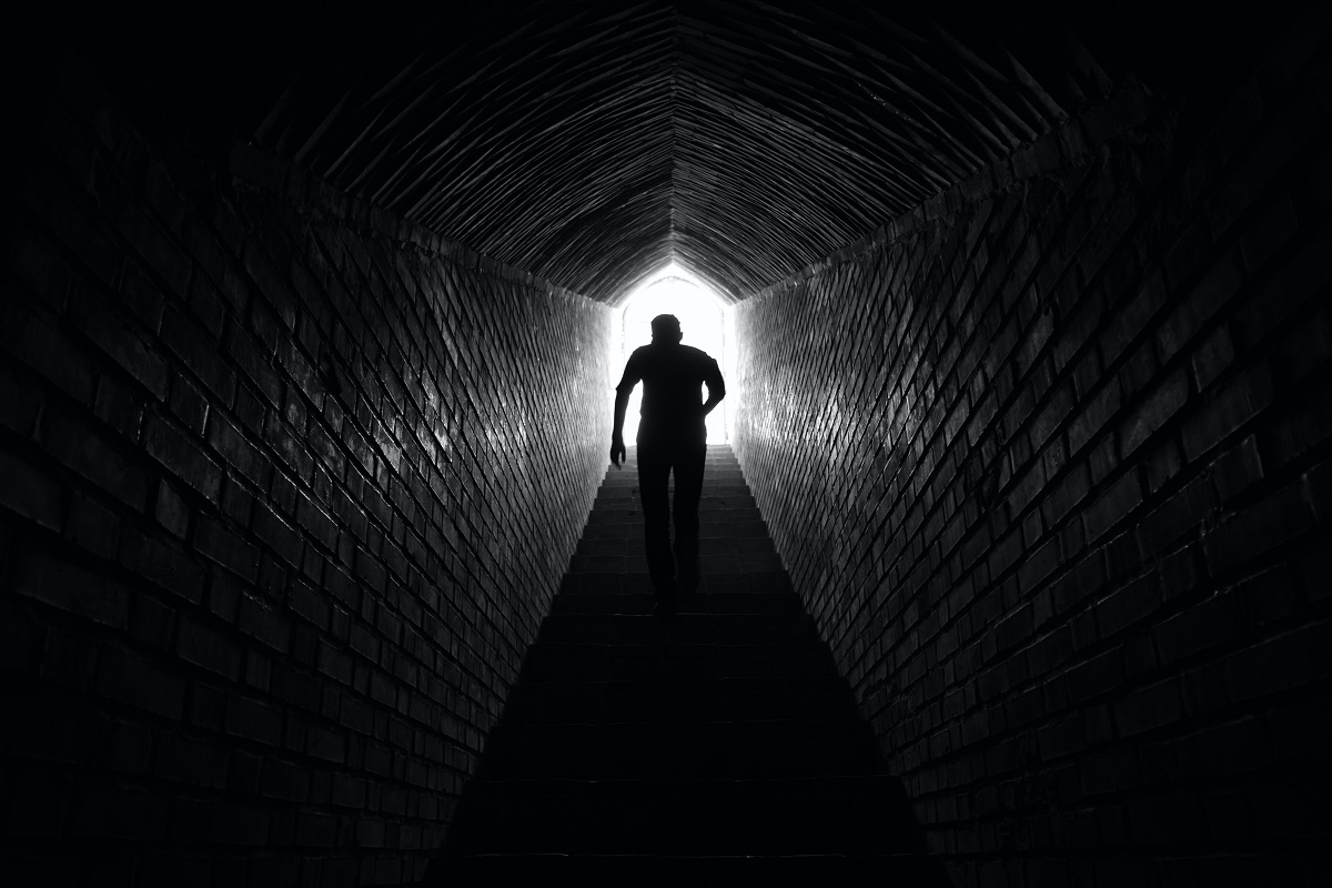 Person walking to light at the end of a tunnel
