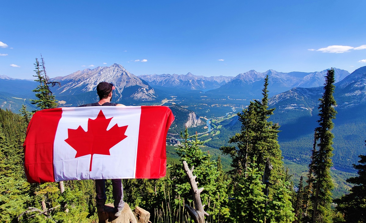 Canadian flag held in front of valley
