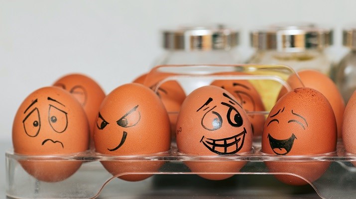 Eggs in a basket tray in a fridge with cartoon faces drawn on them