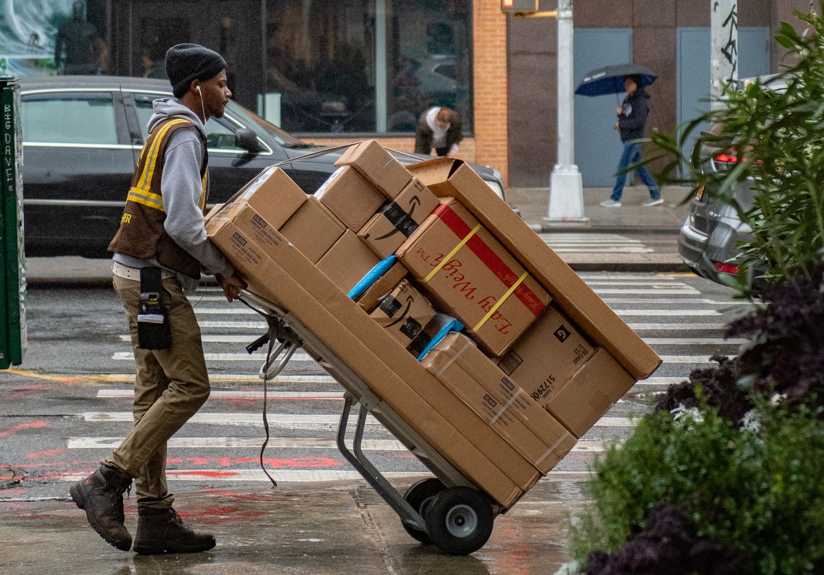Package deliveryman with trolley full of boxes